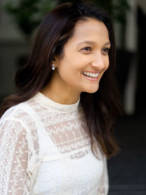 Sangi Carter in a white lace top, smiling